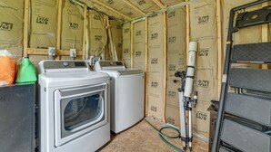 A laundry room with two washing machines and a dryer, surrounded by insulation and construction materials. - Catskills Airstream! Pavilion & Fire Pit Access (Franklin)