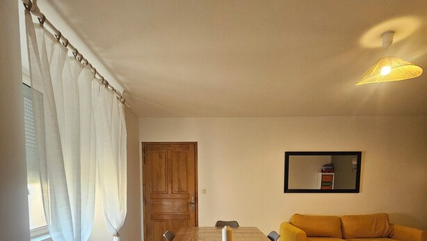 Un'area pranzo con un tavolo di legno, sedie, una poltrona e uno specchio appeso al muro.