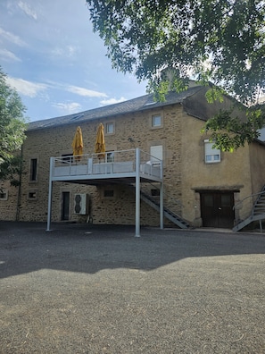 A stone building with a covered outdoor seating area and a staircase leading to a second floor.