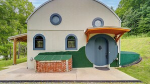 Ein eingeschossiges Gebäude mit abgerundetem Dach, zwei Fenstern und einer Tür mit rundem Fenster darüber.