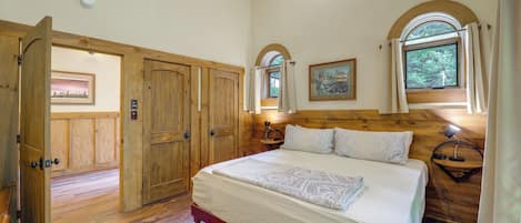 Une chambre avec un grand lit, une armoire en bois et une fenêtre donnant sur un paysage verdoyant.