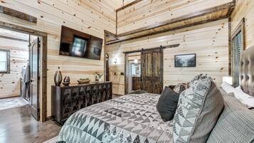 A wooden cabin interior with a bed, a TV, and a rustic decor.
