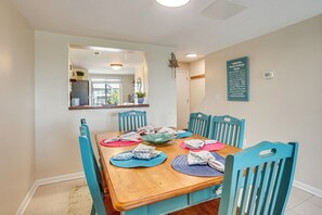 A dining room with a wooden table, blue chairs, and a mirror above the table. - Walk to Beach: Harbor Island Condo w/ Deck (St. Helena Island)