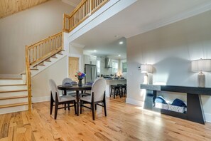 Comedor con escalera de madera, cocina al fondo y zona de bar con una lámpara.