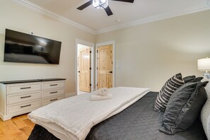 Un dormitorio con cama, cómoda, televisor y ventilador de techo.