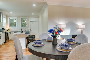 A modern kitchen with white cabinetry, a dining area with a round table, and a vase of flowers. - Helen Family Home w/ Innsbruck Resort Perks! (Helen)