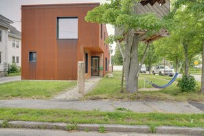A modern building with a flat roof, a visible entrance, and a tree with a hammock. - Shop, Dine, Walk to Deering Oaks! Family Getaway (Portland)