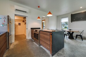 A modern kitchen with a central island, pendant lighting, and a view to the outside. - Shop, Dine, Walk to Deering Oaks! Family Getaway (Portland)