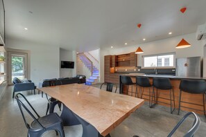 A modern kitchen with a central island, bar stools, and a staircase leading to an upper level. - Shop, Dine, Walk to Deering Oaks! Family Getaway (Portland)