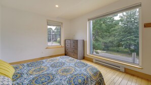 A bedroom with a large window, a bed with a patterned bedspread, a dresser, and a radiator. - Shop, Dine, Walk to Deering Oaks! Family Getaway (Portland)