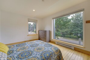 A bedroom with a large window, a bed with a patterned bedspread, a dresser, and a radiator. - Shop, Dine, Walk to Deering Oaks! Family Getaway (Portland)