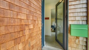 A modern entrance with a wooden exterior wall, a glass door, and a green mailbox. - Shop, Dine, Walk to Deering Oaks! Family Getaway (Portland)