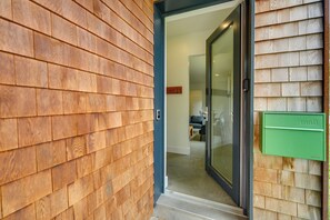 A modern entrance with a wooden exterior wall, a glass door, and a green mailbox. - Shop, Dine, Walk to Deering Oaks! Family Getaway (Portland)