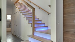 A staircase with wooden steps and a handrail, leading to a landing with a door. - Shop, Dine, Walk to Deering Oaks! Family Getaway (Portland)