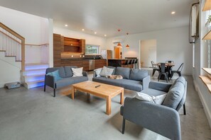 A modern living space with a sofa set, a coffee table, and a dining area with chairs. - Shop, Dine, Walk to Deering Oaks! Family Getaway (Portland)
