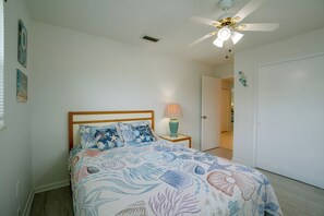 Ein Schlafzimmer mit einem Bett, einem Deckenventilator und einem Nachttisch mit Lampe.
