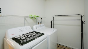 Un cuarto de lavandería con lavadora, secadora y un tendedero de metal.