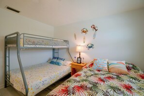 Un lit superposé avec un lit inférieur, une table de chevet avec une lampe et un mur agrémenté d’éléments décoratifs.