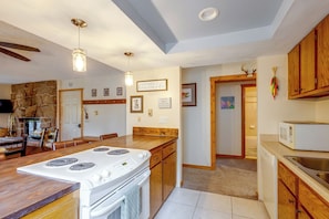 A kitchen with a central island, wooden cabinets, a stove, and a microwave. - Fraser Condo w/ Pool & Hot Tubs: Close to Trails! (Fraser)