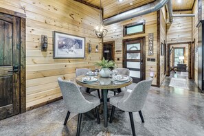 A wooden cabin interior with a dining area featuring a round table, four chairs, and a framed picture on the wall. - Hike, Soak & Play! Luxe Broken Bow Escape (Broken Bow)