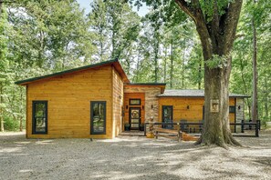 A wooden cabin with a porch, surrounded by trees. - Hike, Soak & Play! Luxe Broken Bow Escape (Broken Bow)