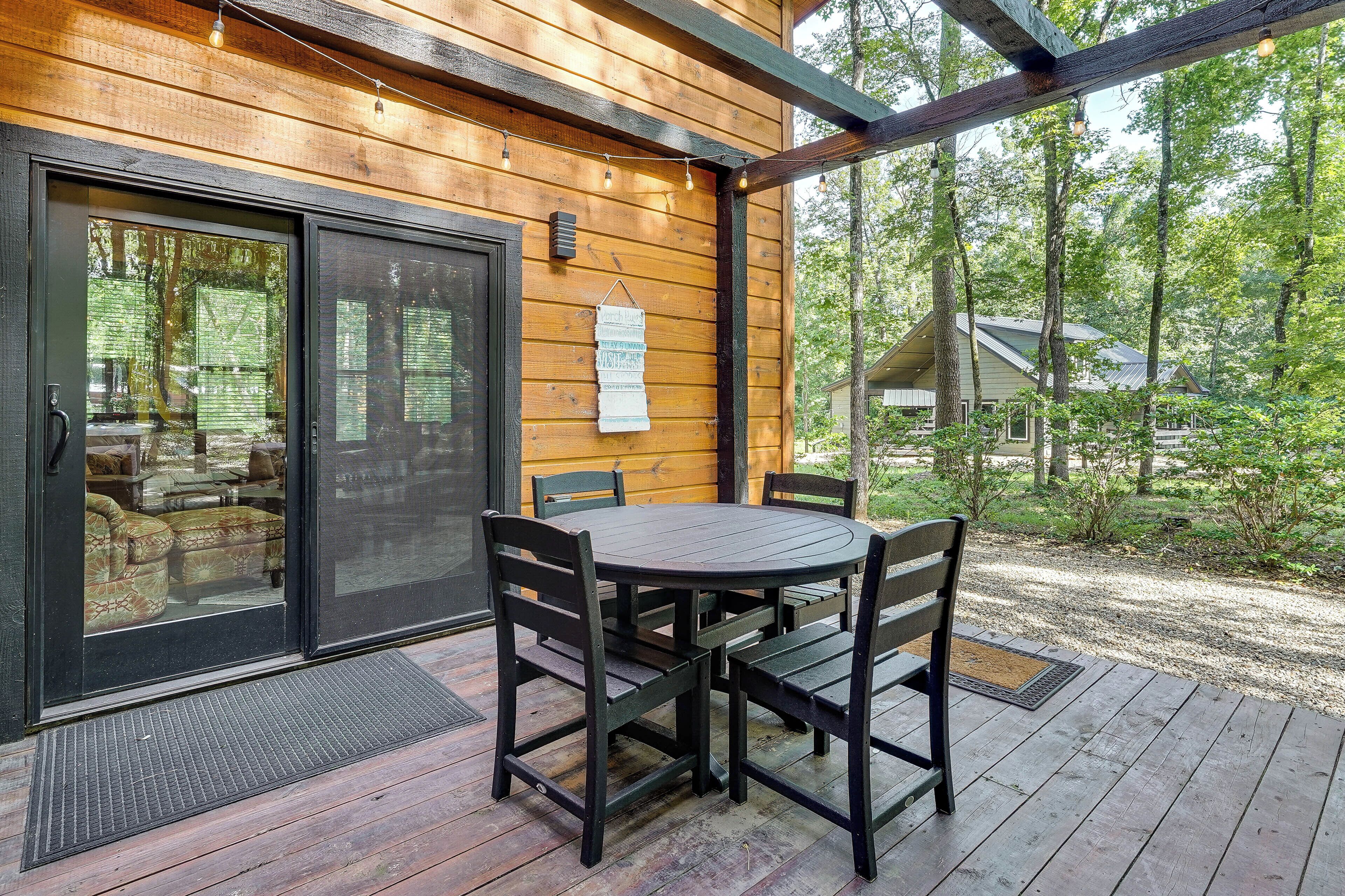 A wooden deck with a table and chairs, a sliding glass door, and a sign on the wall.