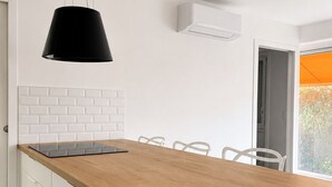 A modern kitchen with a wooden countertop, white cabinets, a black pendant light, and a view of the outdoors. - Renovated one-bedroom apartment on the Arcachon Bay, right on the beach (Arcachon)