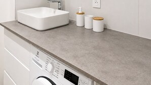 A modern bathroom with a large mirror, a white sink, and a washing machine. - Renovated one-bedroom apartment on the Arcachon Bay, right on the beach (Arcachon)