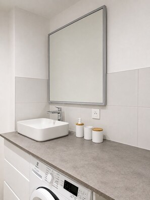 A modern bathroom with a large mirror, a white sink, and a washing machine. - Renovated one-bedroom apartment on the Arcachon Bay, right on the beach (Arcachon)