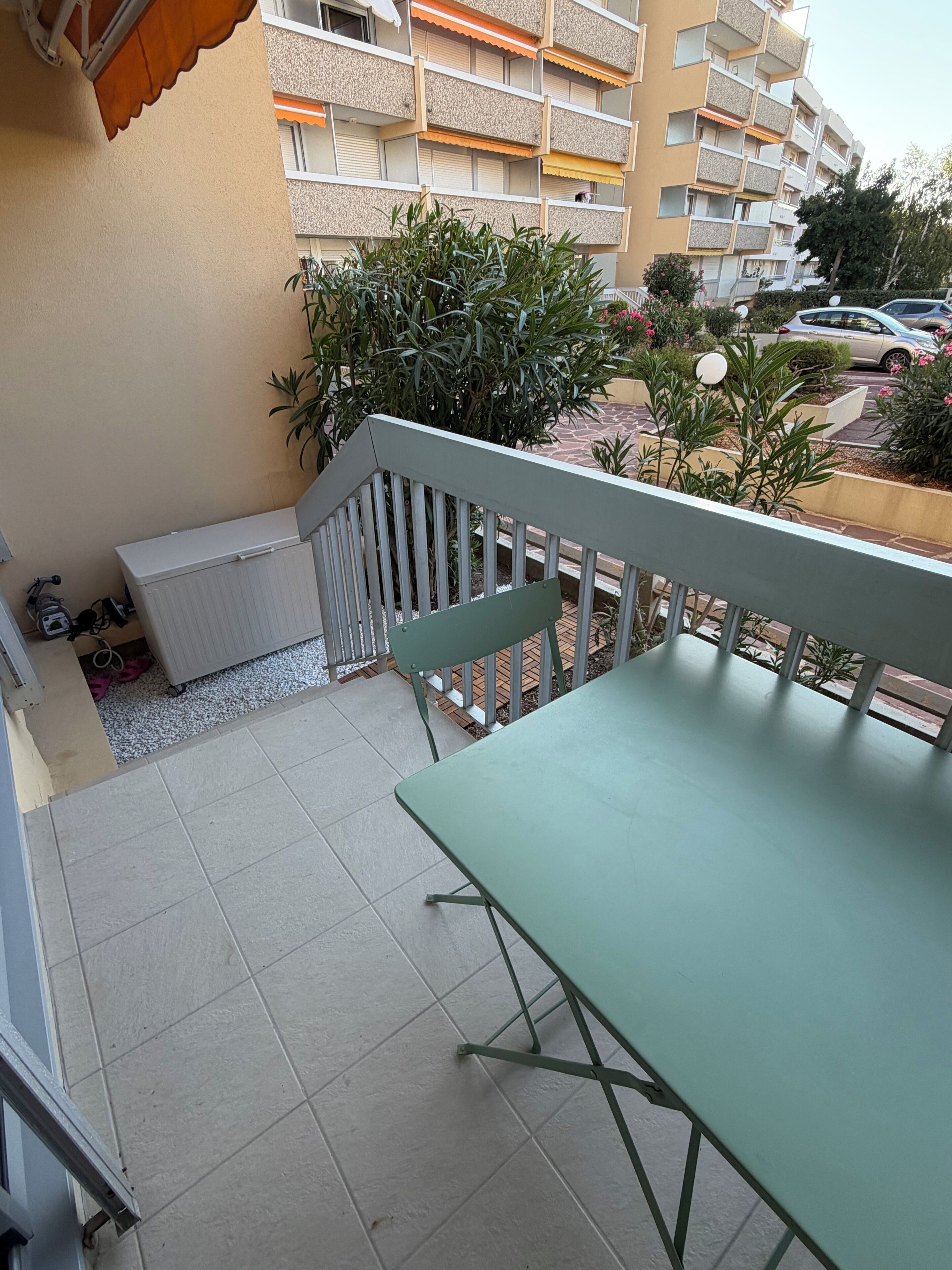 A balcony with a table and chairs, a white radiator, and a potted plant.