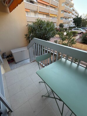 A balcony with a table and chairs, a white radiator, and a potted plant. - Renovated one-bedroom apartment on the Arcachon Bay, right on the beach (Arcachon)