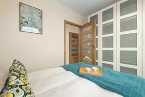 Een slaapkamer met een bed, een houten deur, een witte kledingkast met geëtste panelen en een kaart aan de muur.