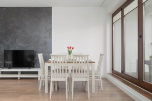 Ein Essbereich mit Tisch, Stühlen, einer Blumenvase und einem Fernseher auf einem Schrank.