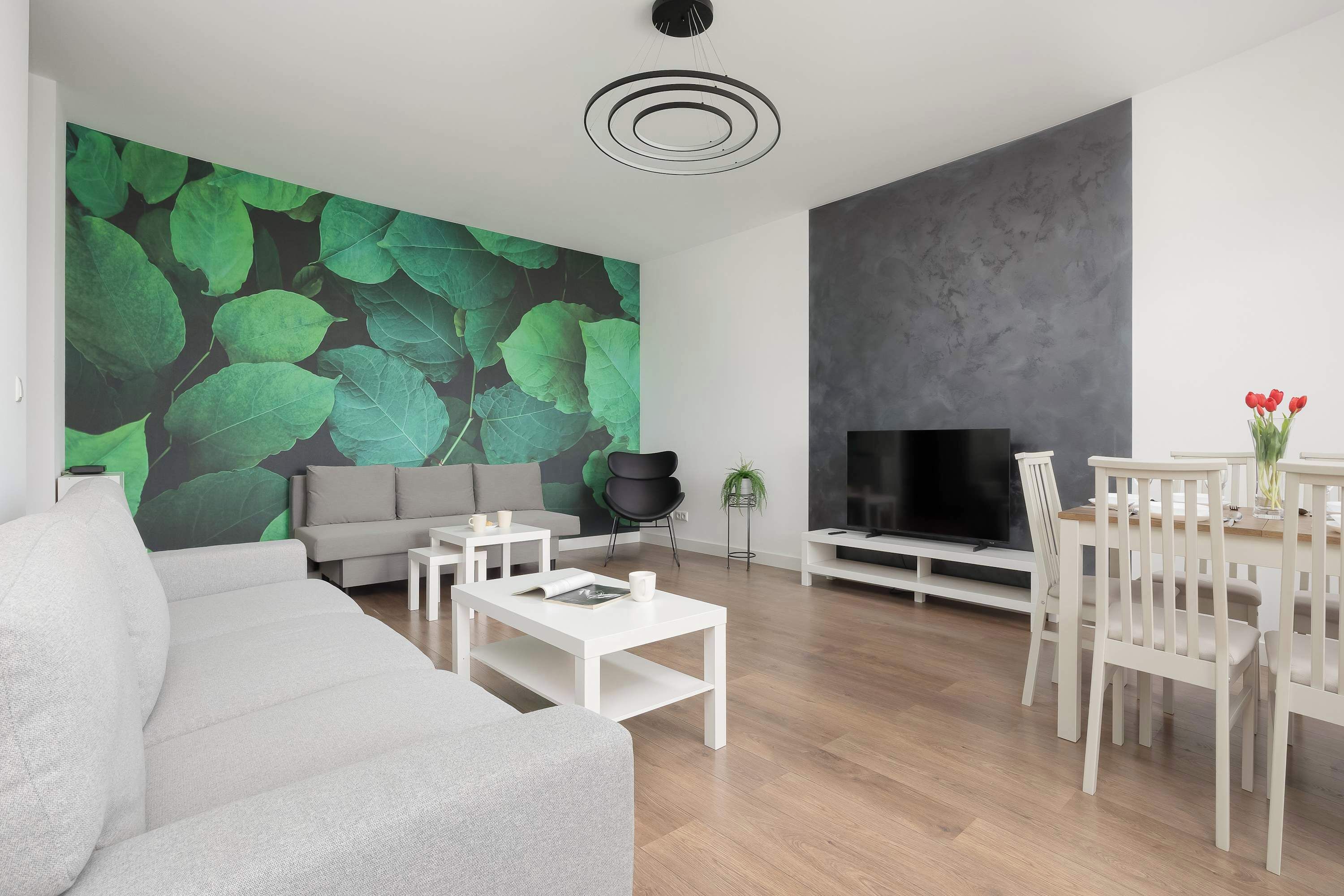 Una sala moderna con un sofá gris, una mesita de centro blanca y un mueble para televisión.