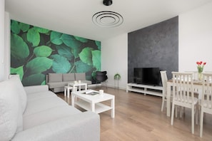 Ein modernes Wohnzimmer mit grauem Sofa, weißem Couchtisch und einem TV-Schrank.