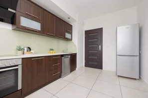 Eine moderne Küche mit dunklen Holzschränken, einem Edelstahlkühlschrank und einem Geschirrspüler.