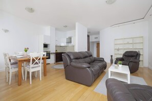 A modern living room with a dining area, a kitchen in the background, and a seating area with a sofa and armchairs. - Air-Conditioned 3 Bedroom Apartment in Warsaw by Noclegi Renters (Warszawa)