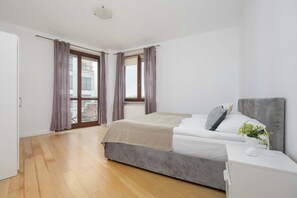 Une chambre à coucher avec un lit, une table de chevet, une fenêtre avec des rideaux et une vue sur l’extérieur.