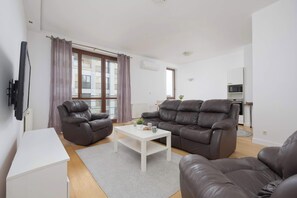 A modern living room with two leather sofas, a white coffee table, and a flat-screen TV mounted on the wall. - Air-Conditioned 3 Bedroom Apartment in Warsaw by Noclegi Renters (Warszawa)