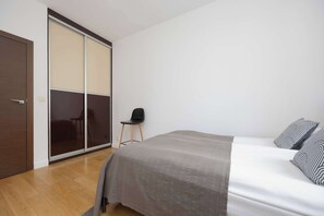 Ein Schlafzimmer mit Bett, Stuhl, Kleiderschrank und einer Schiebetür.