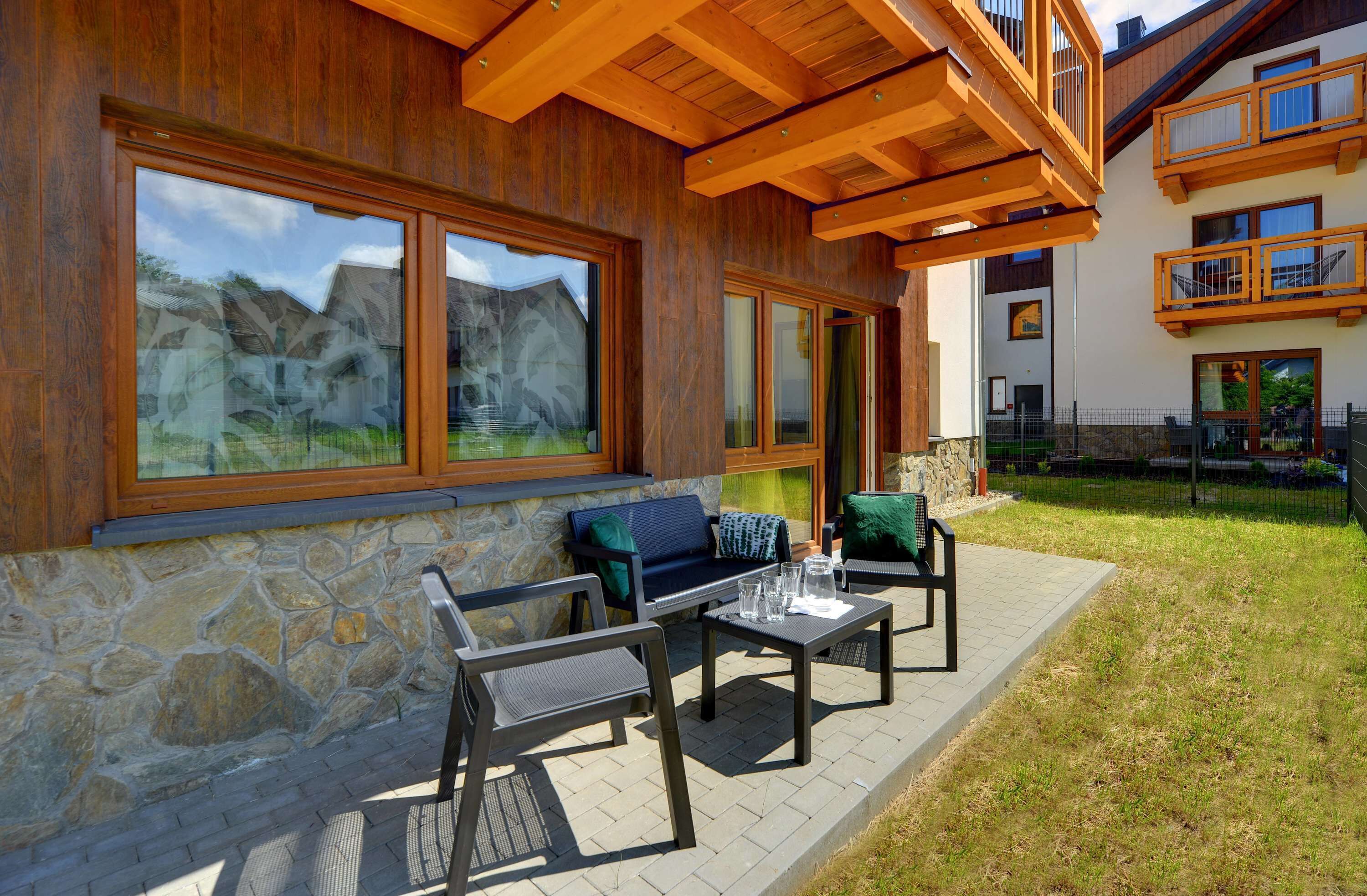 A modern building with large windows, outdoor seating, and a stone facade.
