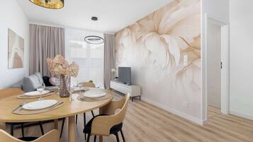 A modern dining area with a round wooden table, chairs, and a vase of flowers.