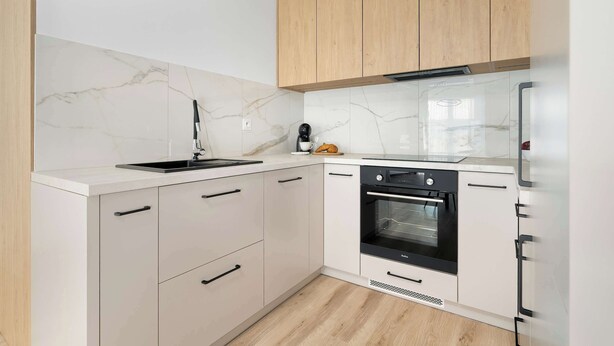 Una cocina moderna con gabinetes blancos, un horno negro y un salpicadero de mármol.