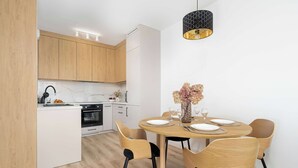 Una cocina moderna con armarios de madera, horno empotrado y comedor con una mesa redonda para cuatro.