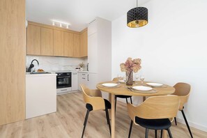 Eine moderne Küche mit Holzschränken, einem eingebauten Backofen und einem Essbereich mit rundem Tisch, gedeckt für vier Personen.