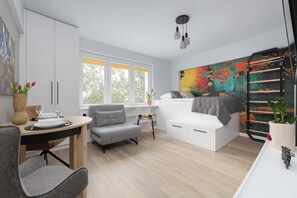 A modern bedroom with a bed, a dining area with a table and chairs, and a large window with a view of trees. - Comfortable Studio in Warsaw | Smart TV (Warszawa)