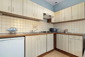 Eine Küche mit hellen Holzschränken, einer Edelstahlspüle, einer Mikrowelle und einem Gasherd.