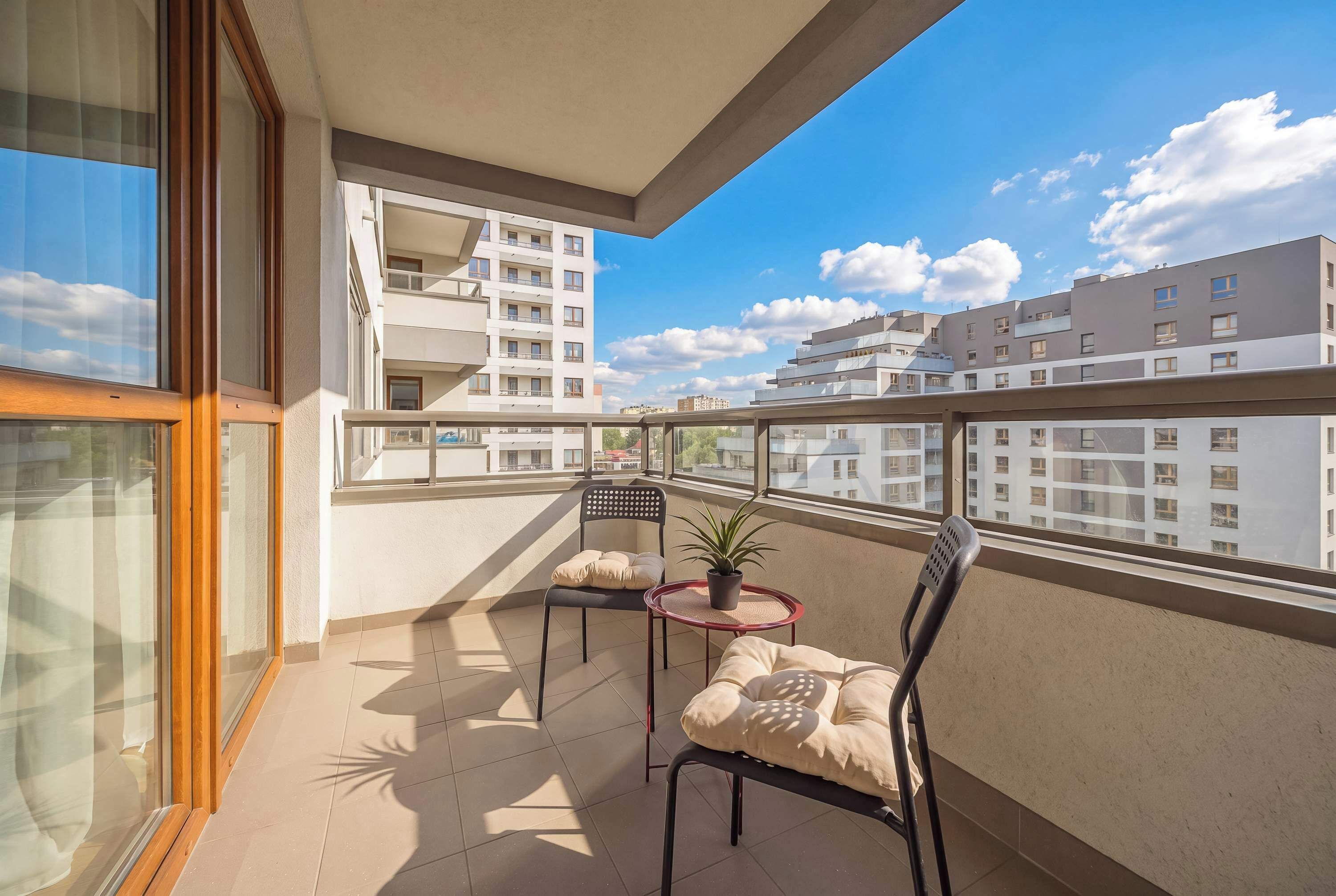 A balcony with two chairs, a small table, and a potted plant.