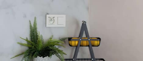 A kitchen with a microwave, a potted plant, and a fruit basket.