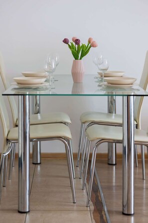 Una mesa de comedor con cuatro sillas, un florero con flores y dos copas de vino.